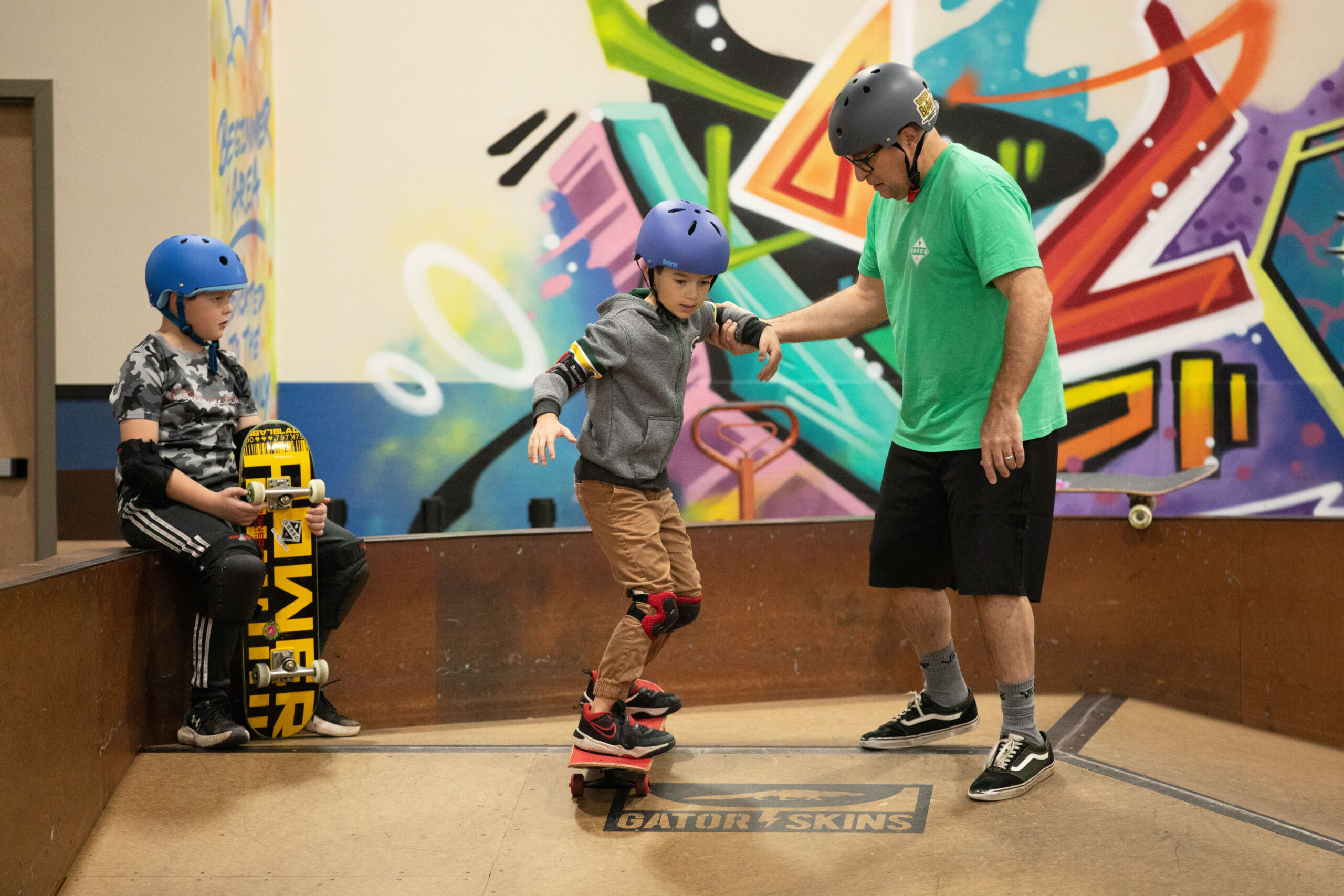 Skateboard coach helping student roll down a ramp