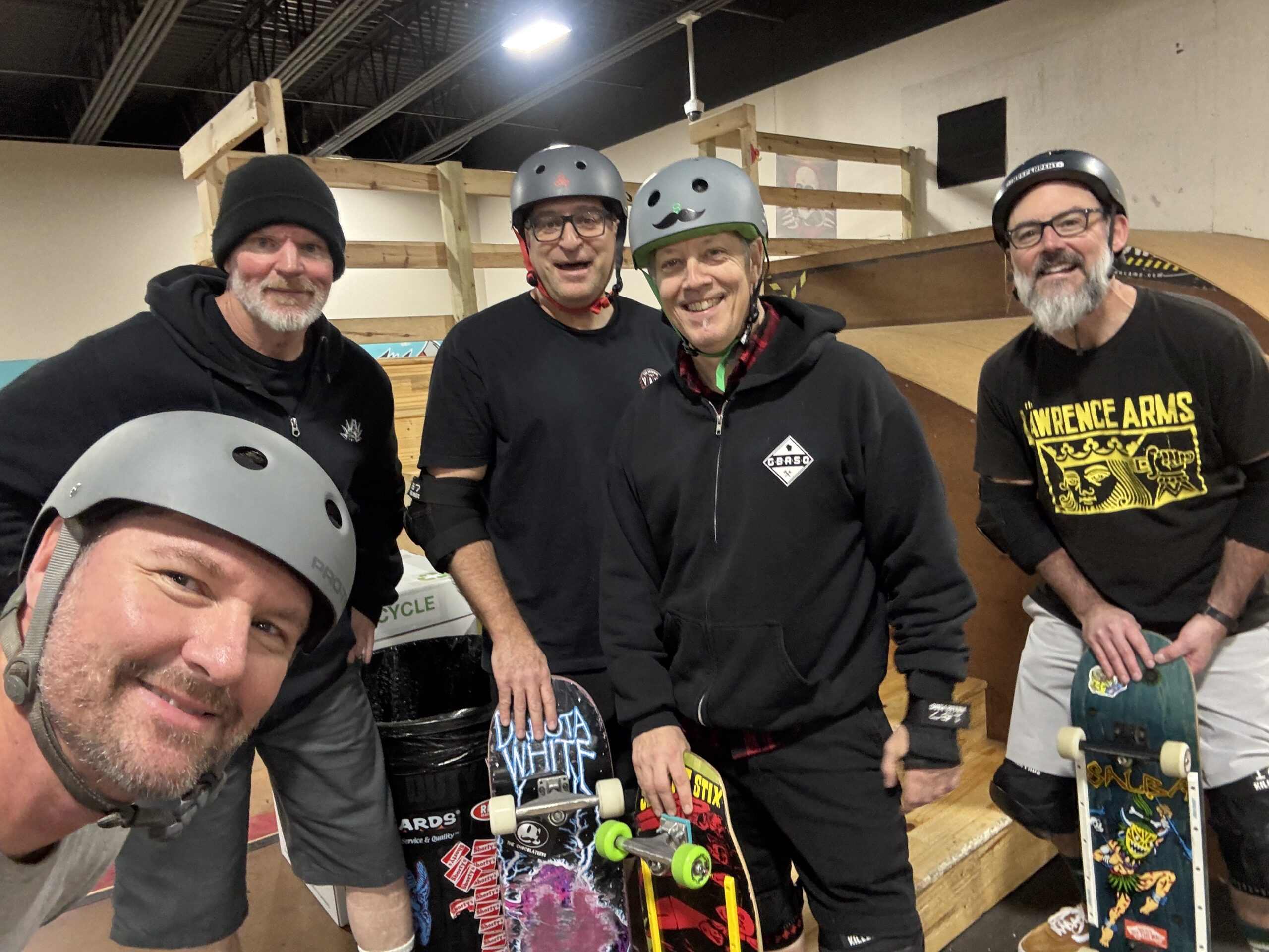 A group of men in helmets pose together while holding their skateboards.