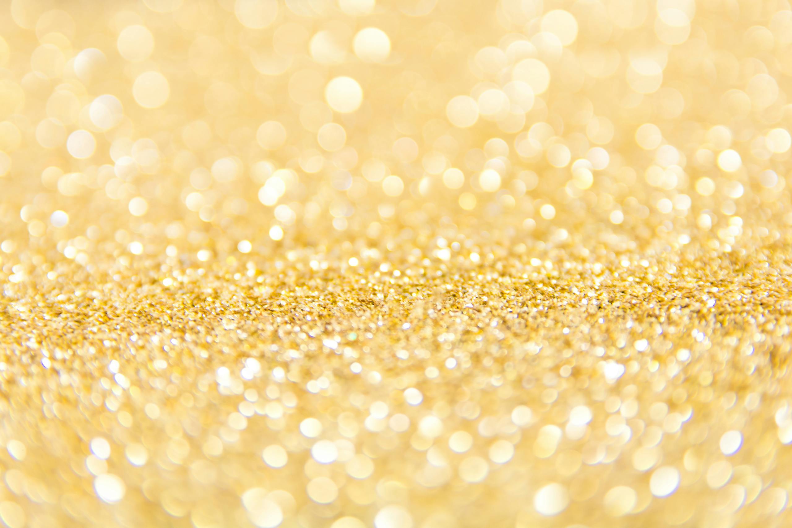 Abstract gold glitter background with a bokeh effect, ideal for festive designs.