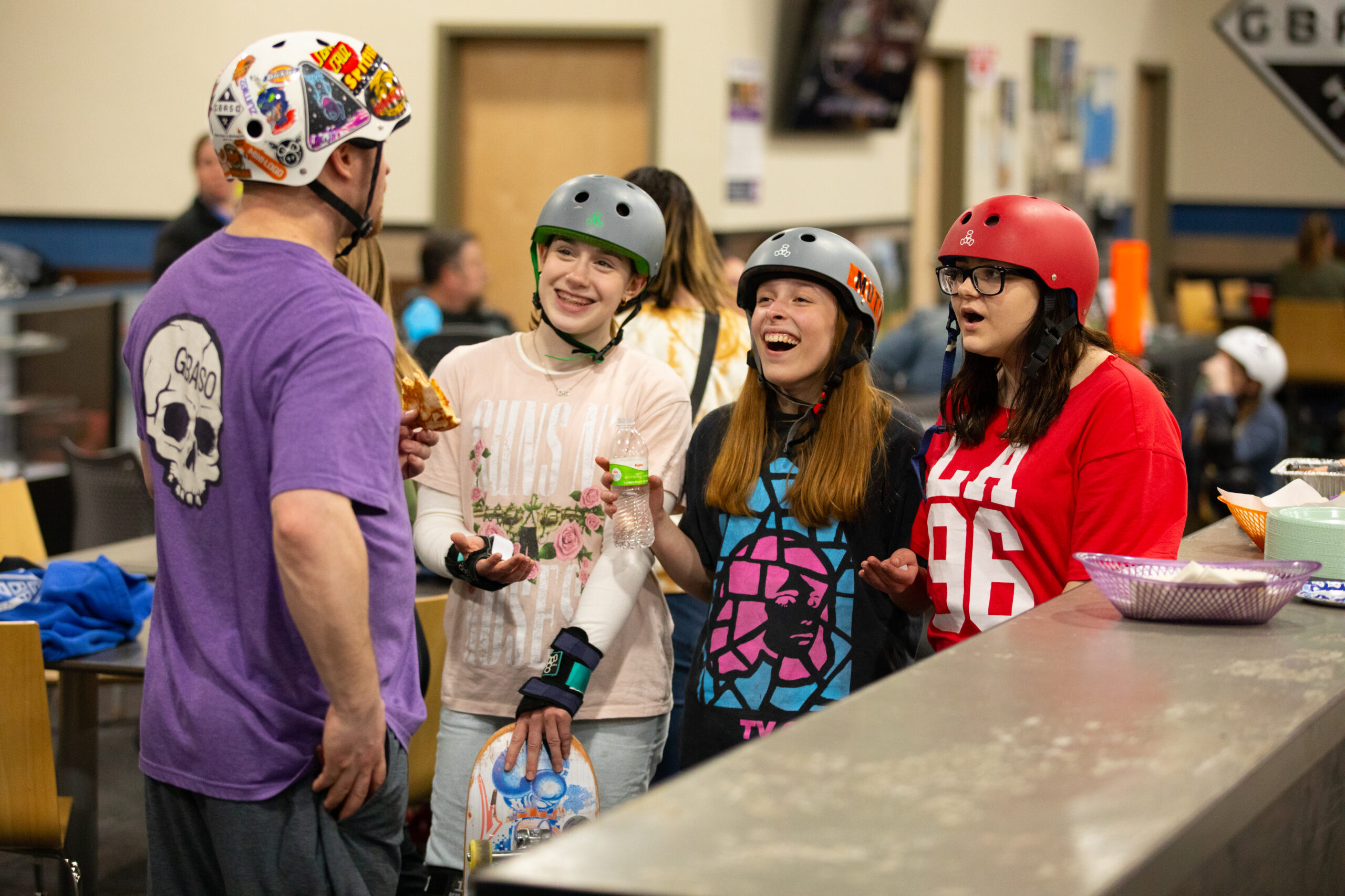 3 female skateboarders interact and laugh with a skate coach at GBASO