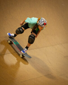 A young skateboarder pumps his skateboard on the vert ramp
