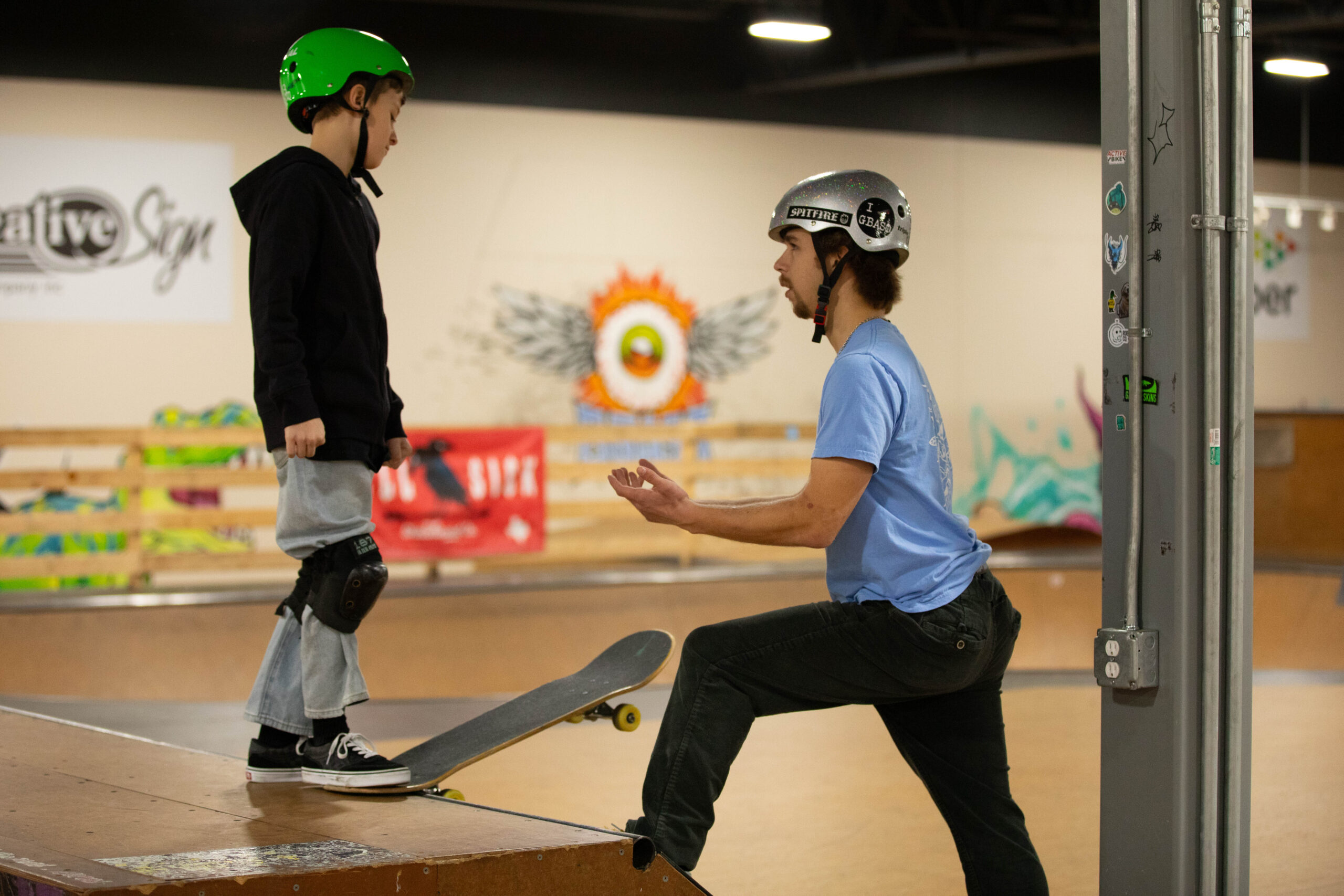 A skateboard coach offers guidance to a young student